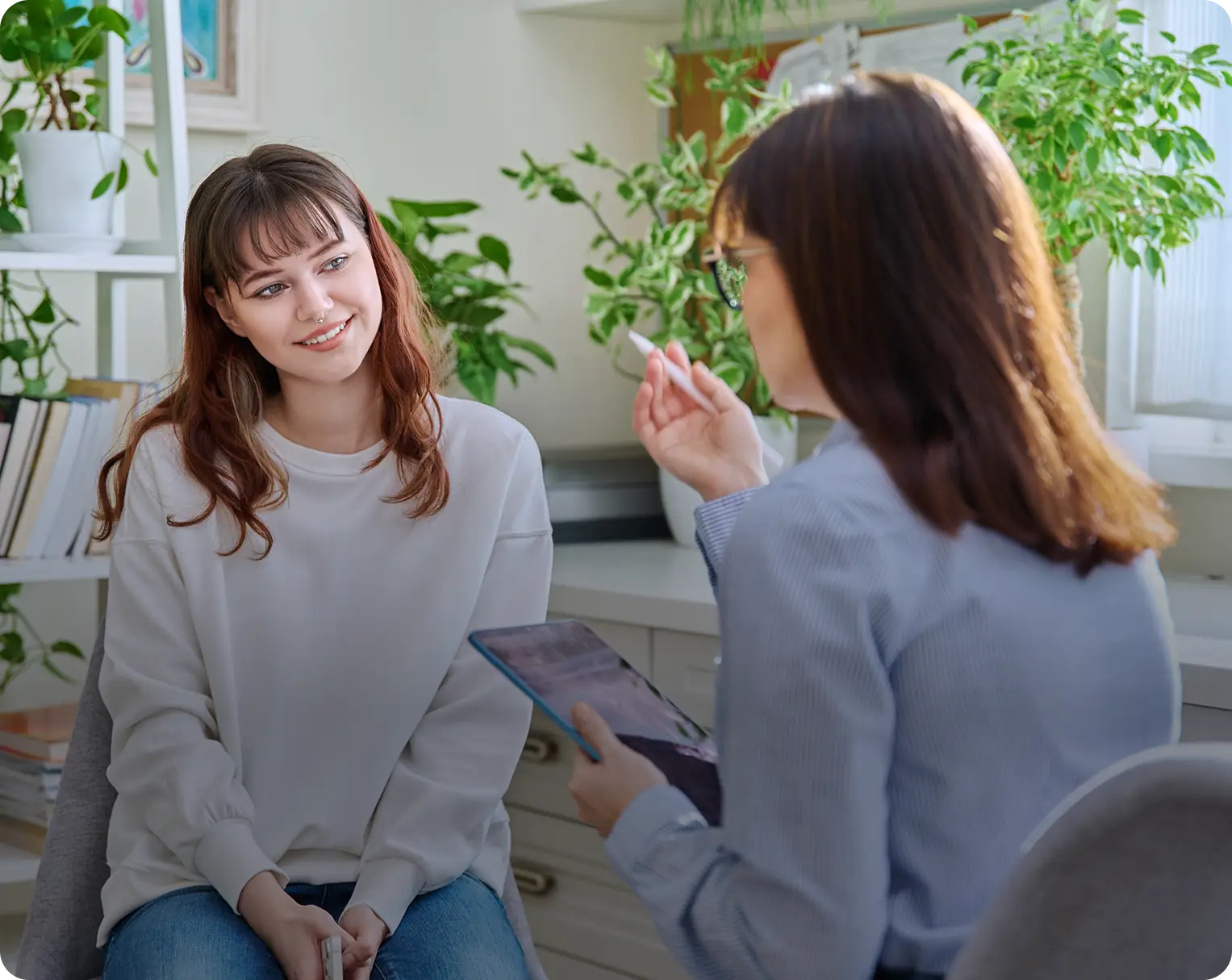 Two women talking in a bright room.